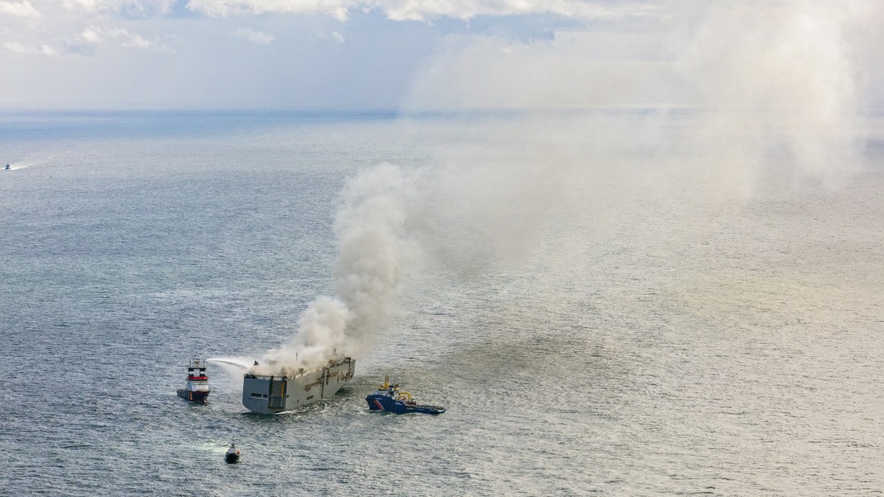 This aerial photograph shows emergency boats extinguishing a fire aboard the Panamanian-registered car carrier cargo ship Fremantle Highway, off the coast of the northern Dutch island of Ameland. One sailor died and several others were injured after a fire broke out on a car carrier ship off the Netherlands on Wednesday, the Dutch coastguard said. Rescue personnel received a call shortly after midnight (2200 GMT Tuesday) saying a fire had started on the Fremantle Highway, a Panamanian-registered ship with 3,000 vehicles on board, about 14.5 nautical miles (27 kilometres) off the northern Dutch island of Ameland. (Photo by Flying Focus / ANP / AFP) / Netherlands OUT