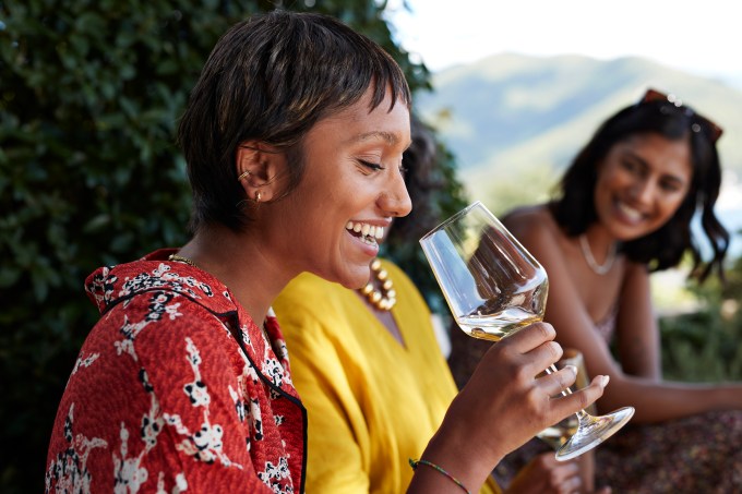 Happy young woman having white wine