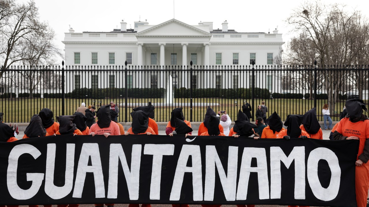 WASHINGTON, DC - JANUARY 11: Activists in orange jumpsuits, representing the 35 men who are still being held at the U.S. detention facility in Guantanamo Bay, Cuba, participate in a protest in front of the White House on January 11, 2023 at Lafayette Square in Washington, DC. Activists staged a demonstration to mark the 21 years since the first prisoners were brought to Guantanamo Bay and to demand that President Joe Biden close the facility and end indefinite military detention. (Photo by Alex Wong/Getty Images)