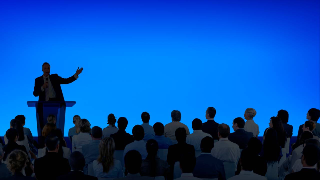 Corporate businessman giving a presentation to a large audience