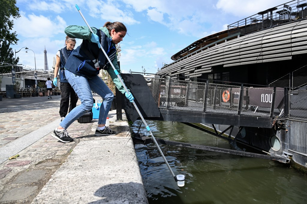 Uma funcionária da empresa Fluidion coleta uma amostra de água do Sena para analisar sua composição antes de evento pré-Olímpico de natação, em Paris. 04/08/2023