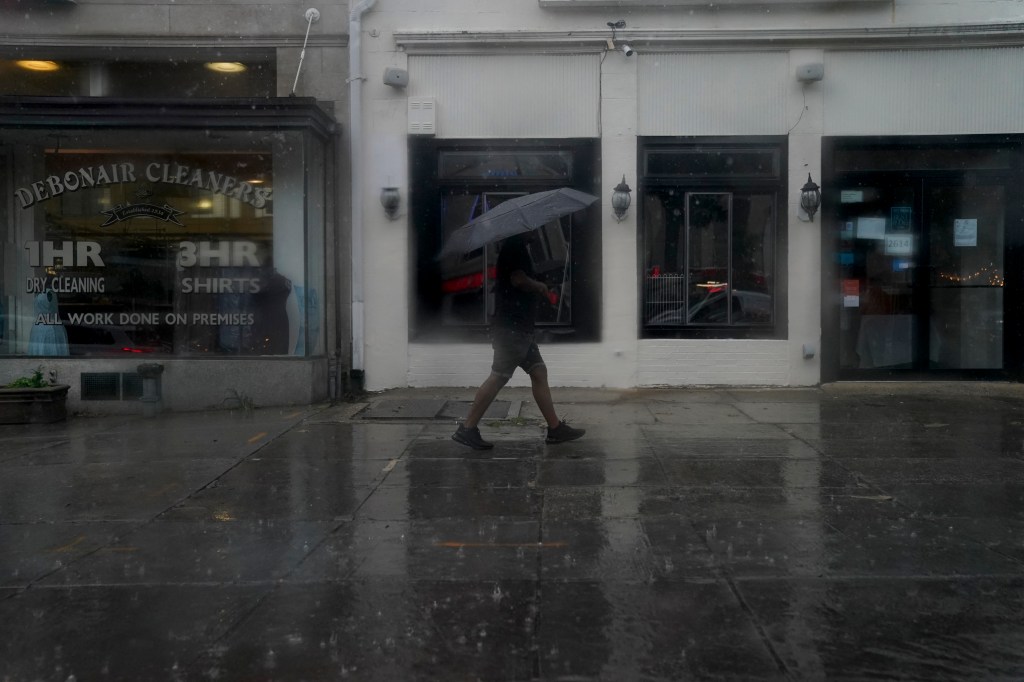 A pedestrian carries an umbrella while walking through rain in Washington, DC, on August 7, 2023. A tornado watch is in effect for the area, with heavy rain, strong winds, and hail expected. (Photo by Stefani Reynolds / AFP)