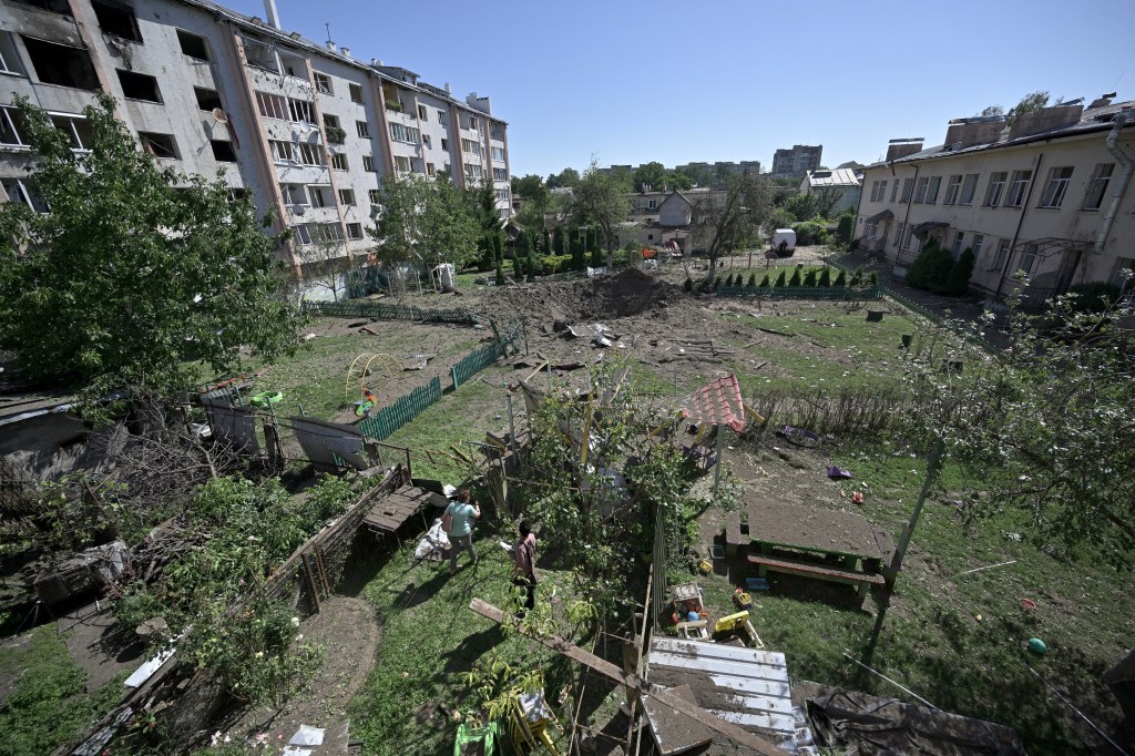 Local residents look at the crater of a missile that fell between residential buildings and a kindergarten in the city of Lviv, western Ukraine, on August 15, 2023, amid Russian invasion in Ukraine. Lviv Mayor Andriy Sadovyi said on the messaging app Telegram that, "many missiles were shot down", but that "residential buildings got hit" in the strike, adding, "more than 100 apartments were damaged, more than 500 windows were broken, and a kindergarten was destroyed" after a missile flew into its yard. (Photo by Genya SAVILOV / AFP)