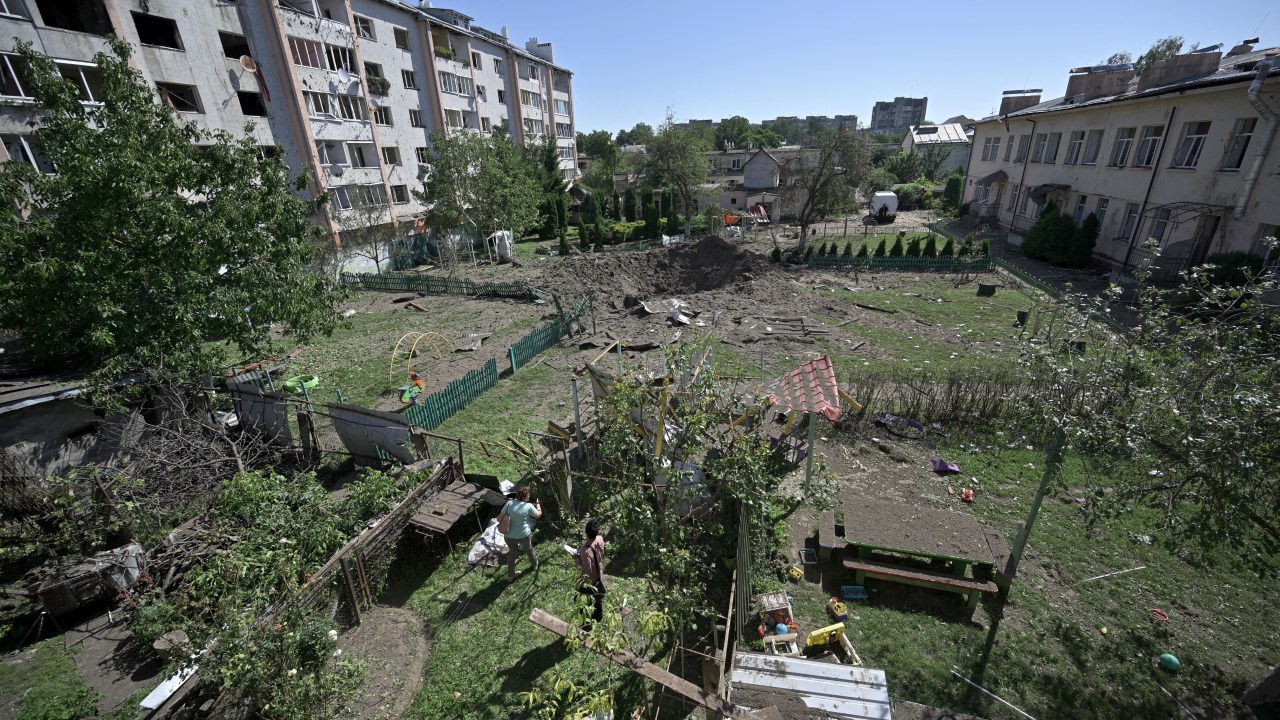 Local residents look at the crater of a missile that fell between residential buildings and a kindergarten in the city of Lviv, western Ukraine, on August 15, 2023, amid Russian invasion in Ukraine. Lviv Mayor Andriy Sadovyi said on the messaging app Telegram that, "many missiles were shot down", but that "residential buildings got hit" in the strike, adding, "more than 100 apartments were damaged, more than 500 windows were broken, and a kindergarten was destroyed" after a missile flew into its yard. (Photo by Genya SAVILOV / AFP)