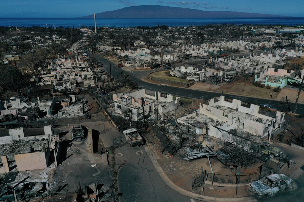 An aerial image shows destroyed homes and vehicles after a wind driven wildfire burned from the hills through neighborhoods to the Pacific Ocean, as seen in the aftermath of the Maui wildfires in Lahaina, Hawaii, on August 17, 2023. Embattled officials in Hawaii who have been criticized for the lack of warnings as a deadly wildfire ripped through a town insisted on August 16 that sounding emergency sirens would not have saved lives. At least 110 people died when the inferno levelled Lahaina last week on the island of Maui, with some residents not aware their town was at risk until they saw flames for themselves. (Photo by Patrick T. Fallon / AFP)