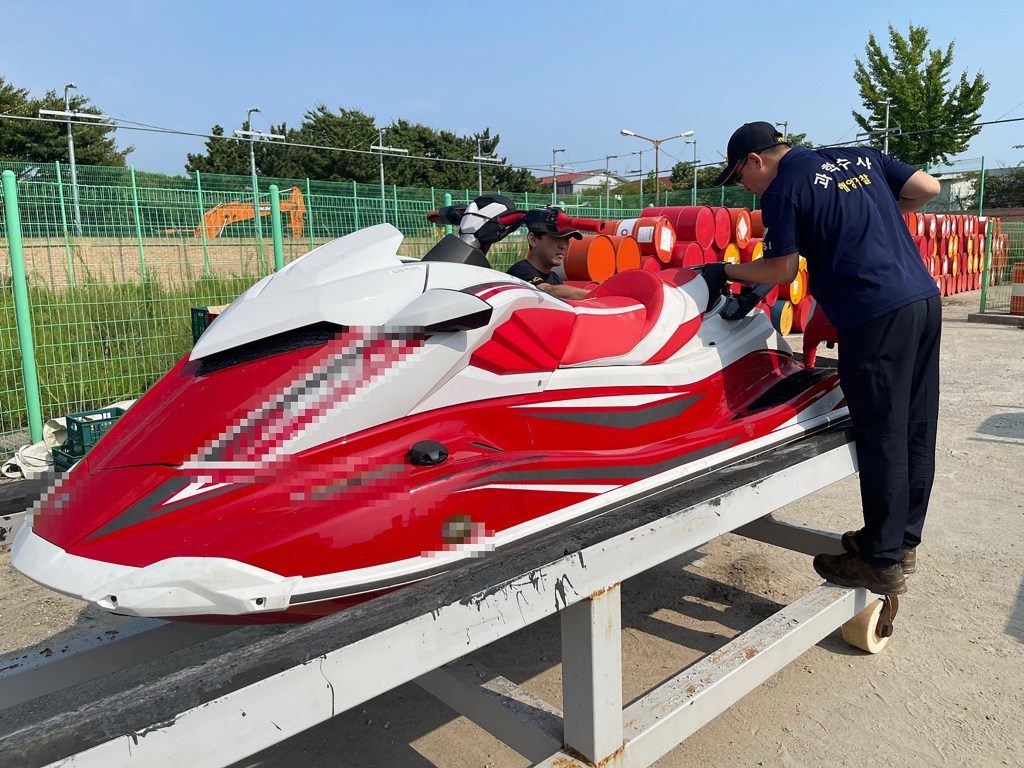 An undated handout photo made available by Korea Coast Guard shows two Coast Guard personel looking at a jet ski in Incheon, after the Coast Guard confirmed it had arrested a Chinese man who "attempted to smuggle into" the western port city of Incheon last week on the jet ski from China's Shandon. A man who crossed from China to South Korea on a jet ski on a 300 plus kilometre voyage is an asylum seeking human rights activist, his representative told AFP, who has been an outspoken critic of Chinese leader Xi Jinping and was jailed for it.  (Photo by Korea Coast Guard / AFP) / RESTRICTED TO EDITORIAL USE - MANDATORY CREDIT "AFP PHOTO / KOREA COAST GUARD " - NO MARKETING NO ADVERTISING CAMPAIGNS - DISTRIBUTED AS A SERVICE TO CLIENTS