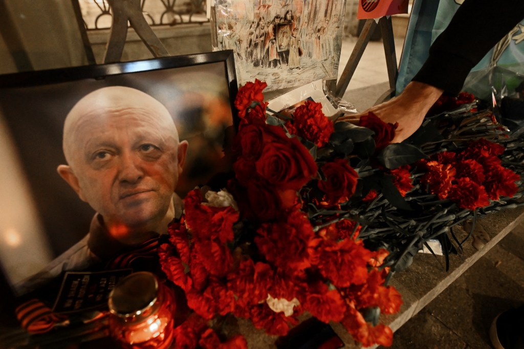 A man lays flowers at the makeshift memorial in honor of Yevgeny Prigozhin and Dmitry Utkin, a shadowy figure who managed Wagner's operations and allegedly served in Russian military intelligence, in Moscow, on August 24, 2023. Russian state-run news agencies on August 23, 2023 said that Yevgeny Prigozhin, the head of the Wagner group that led a mutiny against Russia's army in June, was on the list of passengers of a plane that crashed near the village of Kuzhenkino in the Tver Region. (Photo by NATALIA KOLESNIKOVA / AFP)