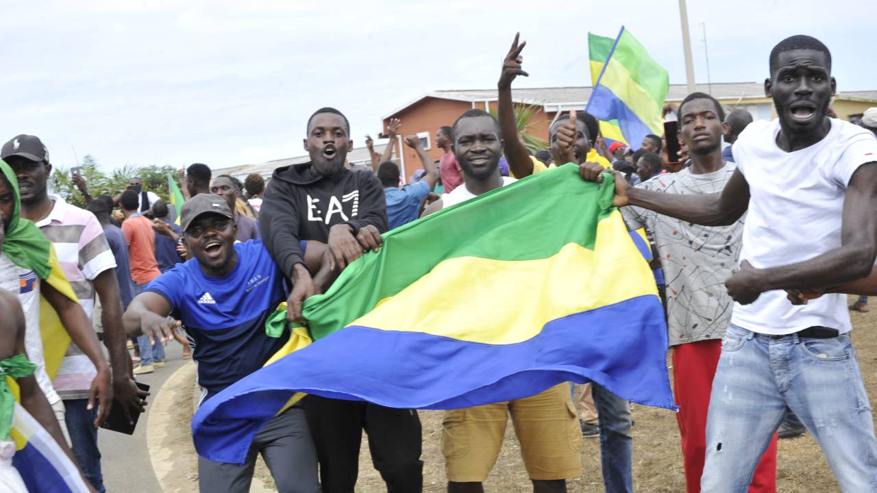 Residents gesture and hold a Gabon national flag as they celebrate in Libreville on August 30, 2023 after a group of Gabonese military officers appeared on television announcing they were "putting an end to the current regime" and scrapping official election results that had handed another term to veteran President Ali Bongo Ondimba. In a pre-dawn address, a group of officers declared "all the institutions of the republic" had been dissolved, the election results cancelled and the borders closed. (Photo by AFP)