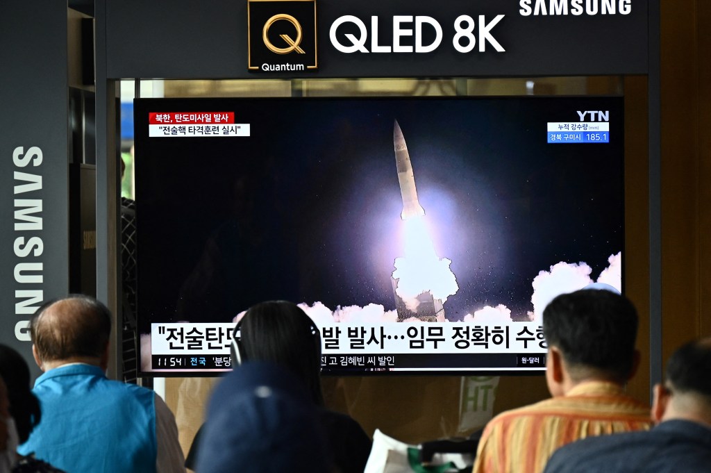 People watch a television showing a news broadcast with a photo of a North Korean missile test, at a railway station in Seoul on August 31, 2023. (Photo by Anthony WALLACE / AFP)
