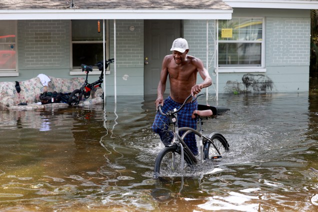Homem tem dificuldade em caminhar com sua bicicleta, em frente à sua casa inundada devido ao furacão Idalia em Crystal River, na Flórida. 31/08/2023 -