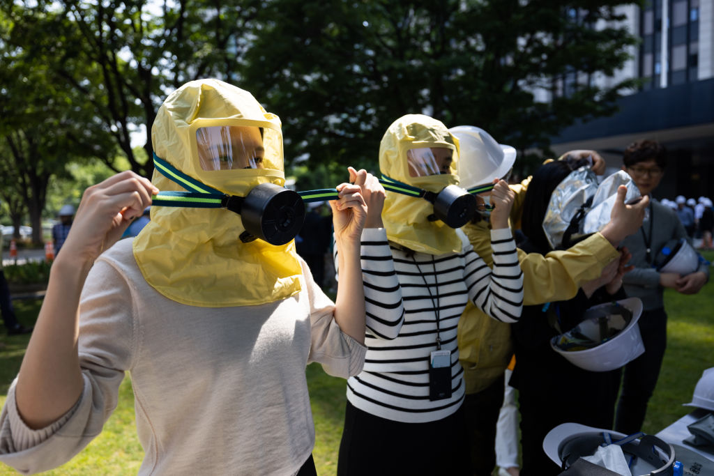 Government employees wear gas masks during a civil air defense drill outside the Government Complex Seoul in Seoul, South Korea, on Tuesday, May 16, 2023. South Korea held nationwide civil defense drills for the first time in six years to step up public preparations as North Korea advances its arsenal of weapons designed to strike its neighbor to the south. Photographer: SeongJoon Cho/Bloomberg via Getty Images