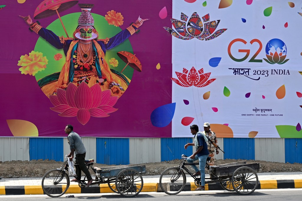 Labourers ride carts past a G20 India summit hoarding along a street in New Delhi on September 5, 2023, ahead of its commencement. (Photo by Arun SANKAR / AFP)