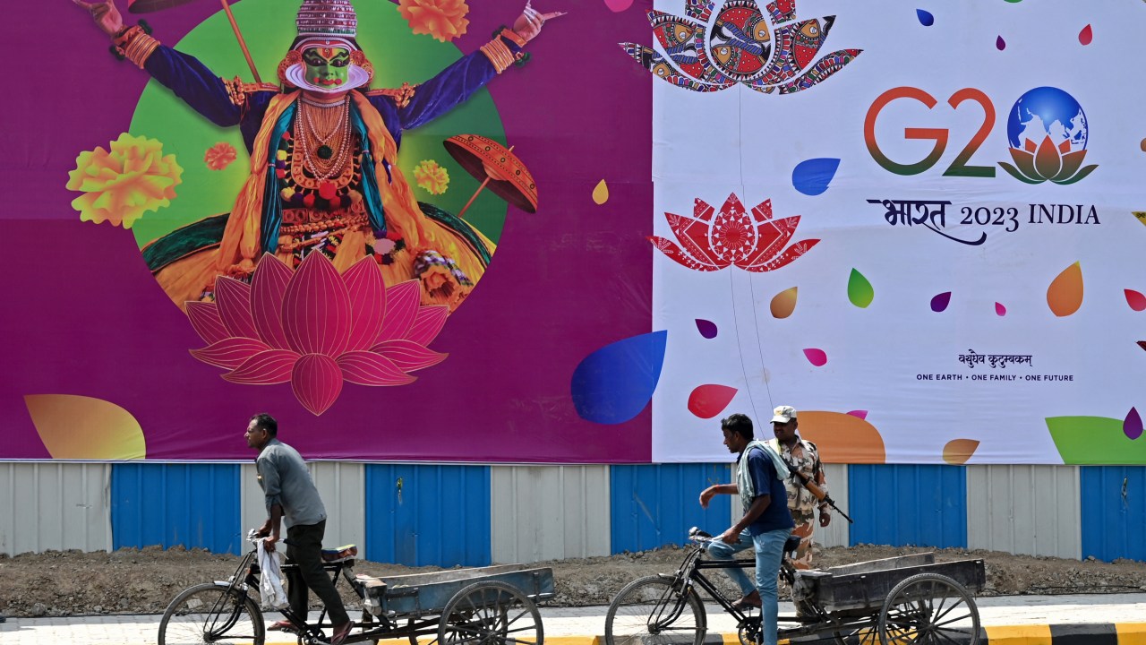 Labourers ride carts past a G20 India summit hoarding along a street in New Delhi on September 5, 2023, ahead of its commencement. (Photo by Arun SANKAR / AFP)