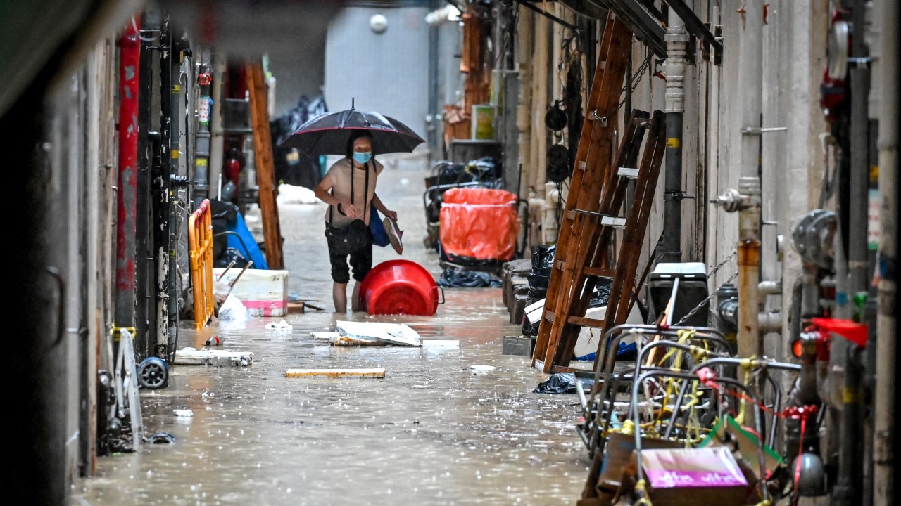 A woman walks in a flooded back alley in Hong Kong on September 8, 2023. Record rainfall in Hong Kong caused widespread flooding in the early hours on September 8, disrupting road and rail traffic just days after the city dodged major damage from a super typhoon. (Photo by Mladen ANTONOV / AFP)