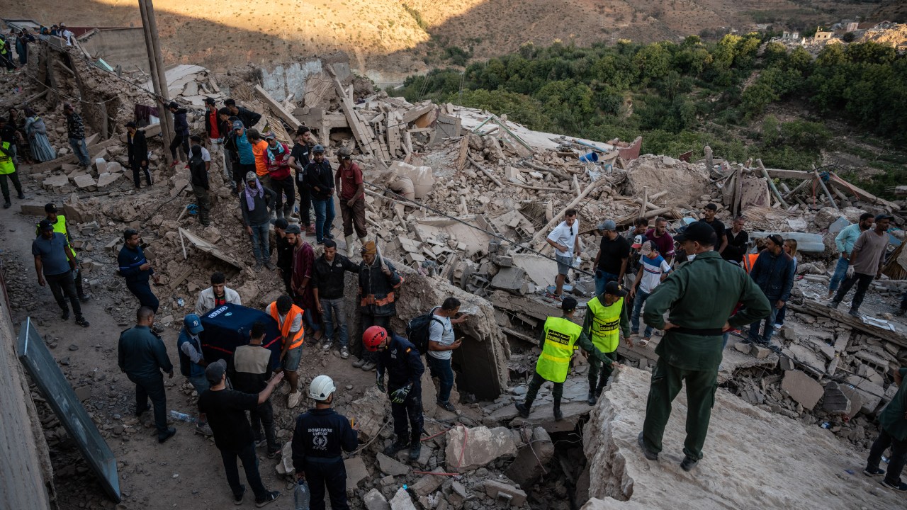 People gather around the rubble of homes in the mountain village of Imi N'Tala, south of Marrakech, on September 10, 2023. The death toll from Morocco's devastating earthquake has risen to 2,497, the interior ministry said on September 11, as search and rescue efforts continue. (Photo by Matias CHIOFALO / AFP)