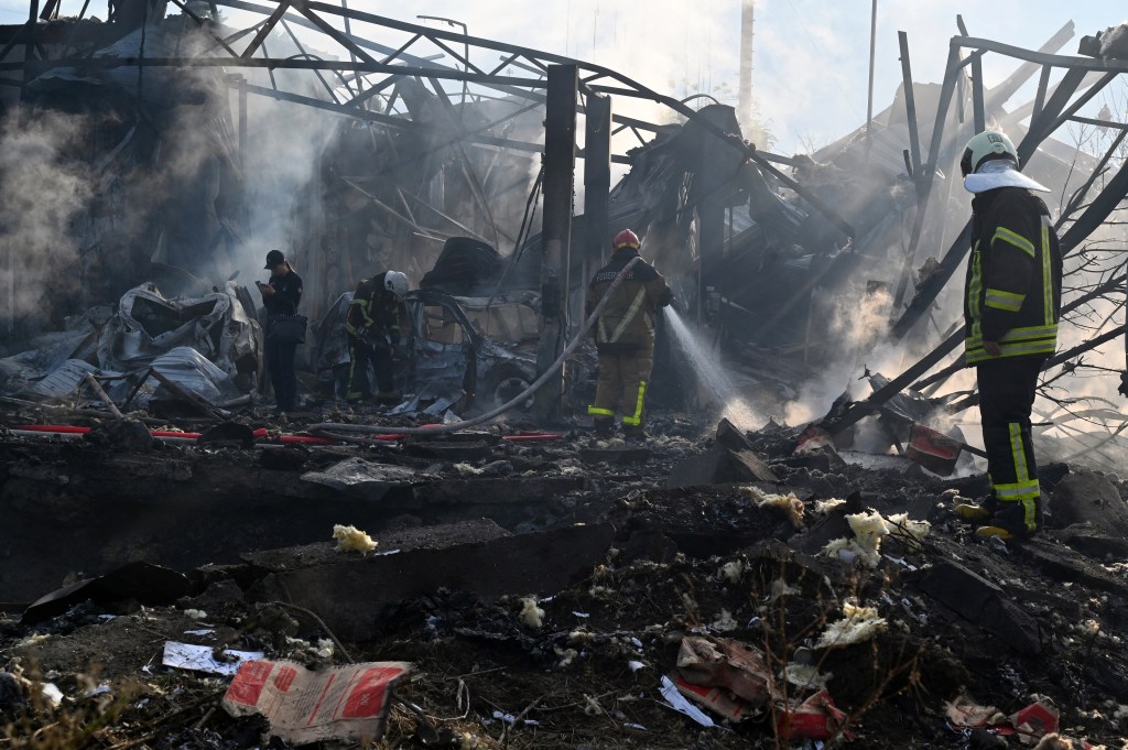 Firefighters push out a fire as police experts look for fragments of missile at a crater on an industrial area of the Ukrainian capital of Kyiv, after a massive overnight missile attack to Ukraine on September 21, 2023. Ukraine said on september 21, 2023 its air defence systems had brought down three dozen Russian cruise missiles overnight in Moscow's latest barrage that left dead and injured throughout the country. (Photo by Sergei SUPINSKY / AFP)