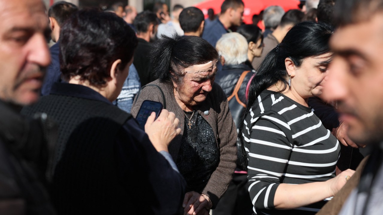 Refugees, including an elderly woman with a head wound she said she got in a car accident as her family fled from Nagorno-Karabakh, wait to pass near a Red Cross registration centre in Goris, on September 27, 2023. Armenia on September 26, 2023, said 28,120 refugees have so far arrived from Nagorno-Karabakh, a majority ethnic Armenian breakaway enclave defeated in a lightning offensive by Azerbaijan last week. (Photo by ALAIN JOCARD / AFP)