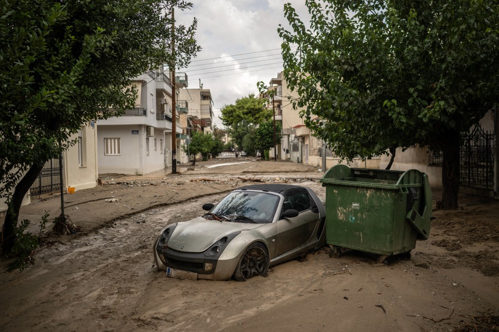 This photograph taken on September 28, 2023 shows a car on a muddy street after the Storm Elias at Volos. Hundreds of people were rescued from floods in Greece overnight and early on September 28, 2023, officials said, as a new storm hit the country just weeks after floods left 17 dead. The fire service said it had assisted over 250 people in the region surrounding the central city of Volos, where a curfew was declared September 27, 2023, as Storm Elias made landfall. (Photo by Angelos TZORTZINIS / AFP)