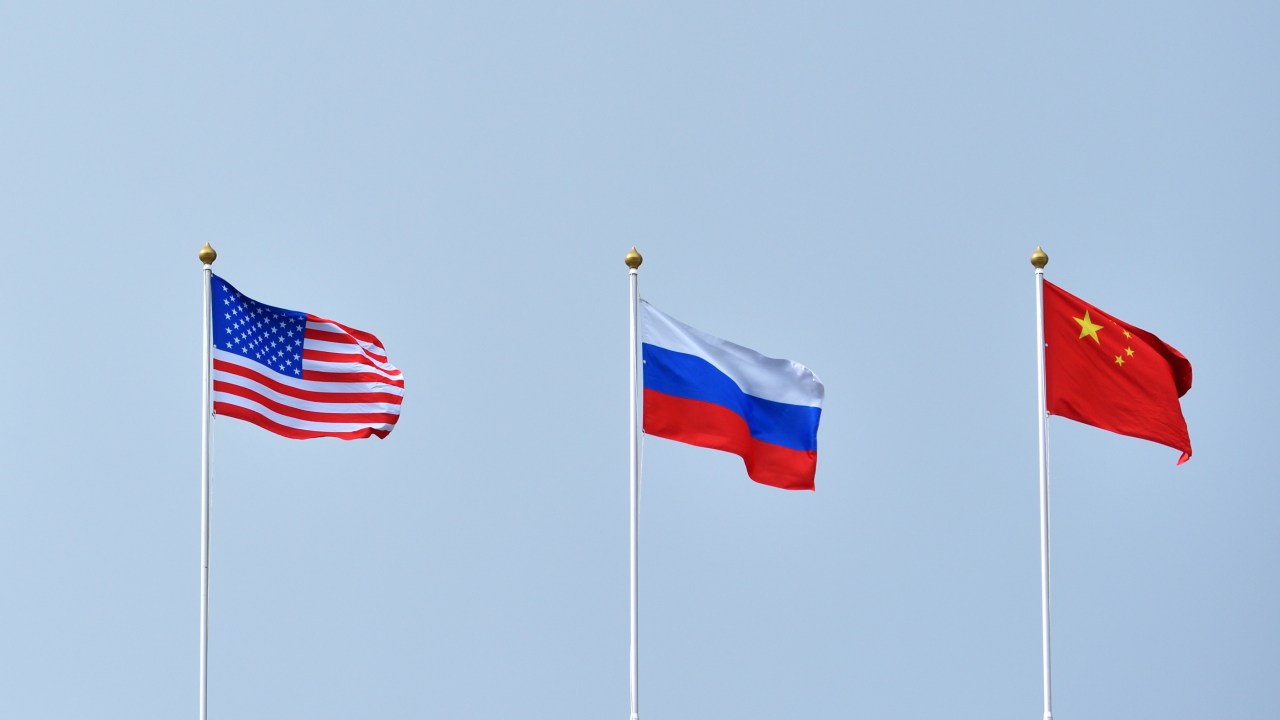 Bandeiras da Rússia, China e Estados Unidos balançando ao vento.