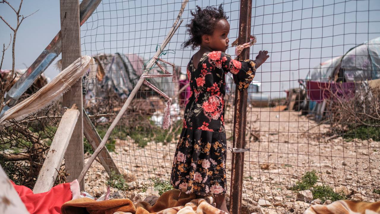(FILES) One of the children of Yurub Abdi Jama stands next to a fence at their home in an informal settlement of internally displaced people in the outskirts of the city of Hargeisa, Somaliland, on September 16, 2021. Weather disasters fueled by climate change -- from floods to droughts, storms to wildfires -- sparked 43.1 million child displacements from 2016 to 2021, the UN Children's Fund warned on October 5, 2023, slamming the lack of attention paid to victims. Statistics on internal displacements caused by climate disasters generally do not account for the age of the victims. But UNICEF worked with the non-governmental Internal Displacement Monitoring Center to unpick the data and reveal the hidden toll on children. From 2016 to 2021, four types of climate disasters (floods, storms, droughts and wildfires) -- the frequency of which has increased due to global warming -- led to 43.1 million child displacements in 44 countries, the report says. (Photo by EDUARDO SOTERAS / AFP)