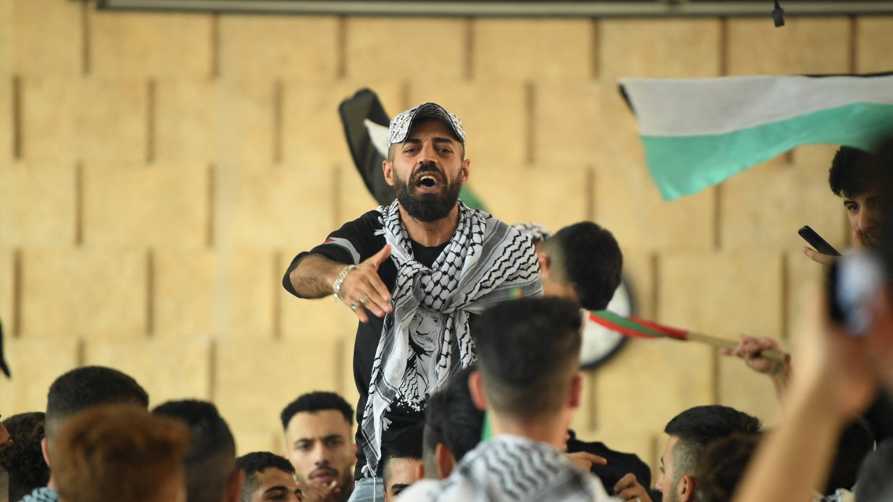 A student from Aleppo University wearing a Palestinian chequerred keffiyeh shouts slogans during a rally in support of the Palestinian cause on campus in the northern Syrian city, on October 11, 2023. The death toll from five days of ferocious fighting between Hamas and Israel rose sharply overnight as Israel kept up its bombardment of Gaza on October 11, after recovering the dead from the last communities near the border where Palestinian militants had been holed up. (Photo by AFP)