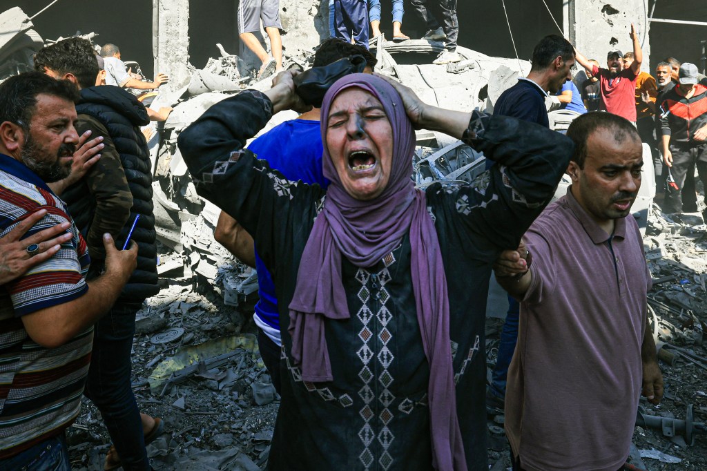 EDITORS NOTE: Graphic content / A Palestinian woman reacts as others rush to look for victims in the rubble of a building following an Israeli strike in Khan Yunis in the southern Gaza Strip on October 17, 2023, amid the ongoing battles between Israel and the Palestinian group Hamas. Thousands of people, both Israeli and Palestinians have died since October 7, 2023, after Palestinian Hamas militants based in the Gaza Strip, entered southern Israel in a surprise attack leading Israel to declare war on Hamas in Gaza on October 8. (Photo by Mahmud HAMS / AFP)