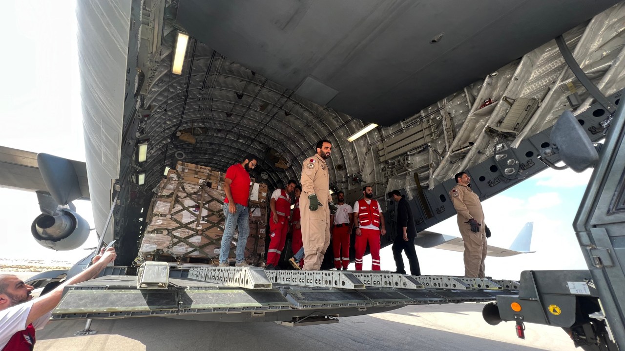 Volunteers from Qatar and Egypts Red Crescent humanitarian organisations unload aid destined for the Palestinians of the Gaza Strip at Egypt's el-Arish airport in the north Sinai peninsula on October 22, 2023, amid the ongoing battles between Israel and the Palestinian group Hamas. A 17-truck aid convoy entered Gaza from Egypt on October 22, 2023, as Israel intensified strikes on the Palestinian enclave facing a "catastrophic" humanitarian situation in the war sparked by Hamas's bloody attack. (Photo by Callum PATON / AFP)