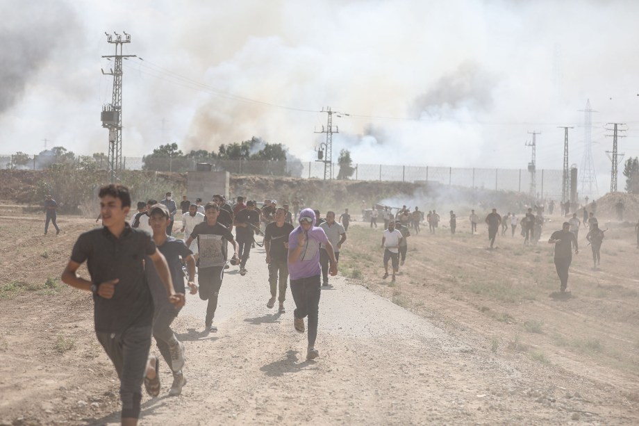 Pessoas correm diante de confrontos entre grupos palestinos e forças de defesa de Israel em Gaza (07/10/2023)