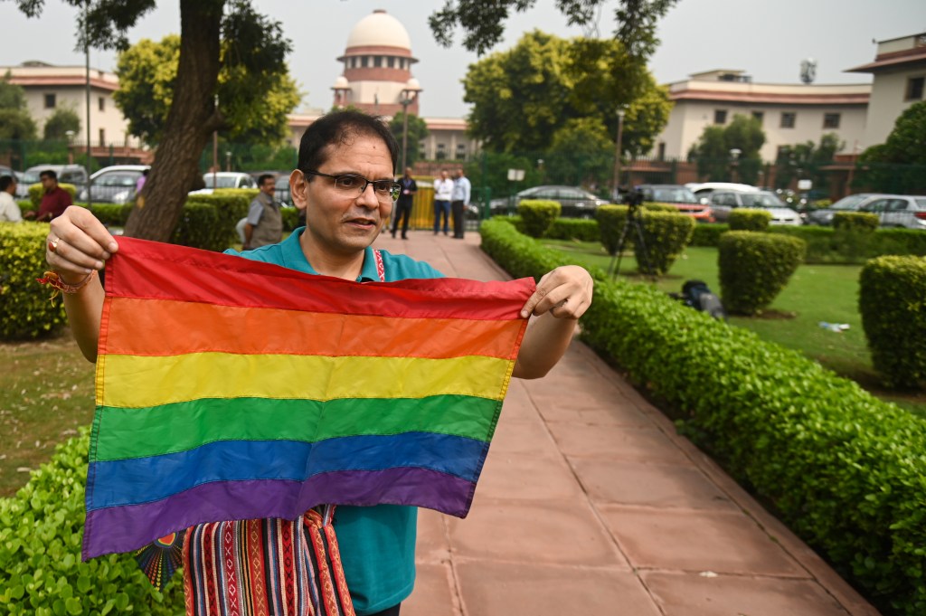 Manifestante segura bandeira da comunidade LGBTQ+ na frente da Suprema Corte. (17/10/2023)