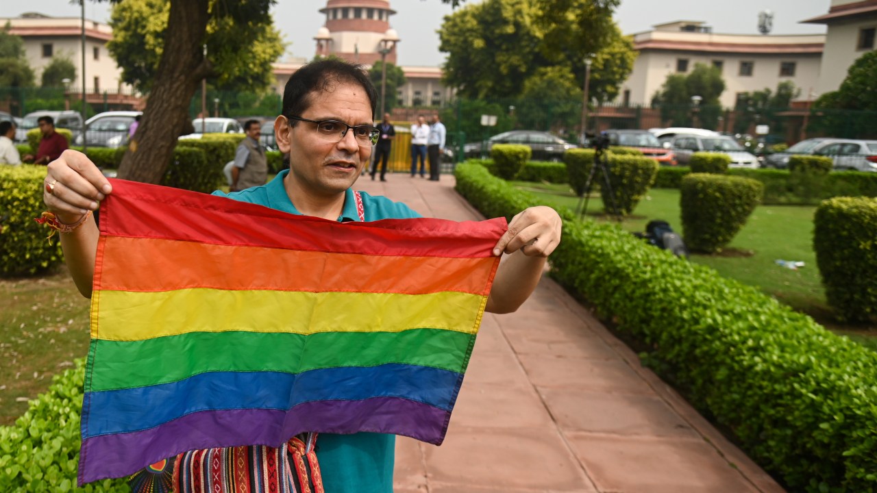 Manifestante segura bandeira da comunidade LGBTQ+ na frente da Suprema Corte. (17/10/2023)