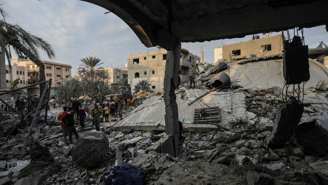 Pessoas vasculham edifícios destruídos durante ataques aéreos israelenses no sul da Faixa de Gaza em 13 de novembro de 2023 em Khan Yunis, Gaza.