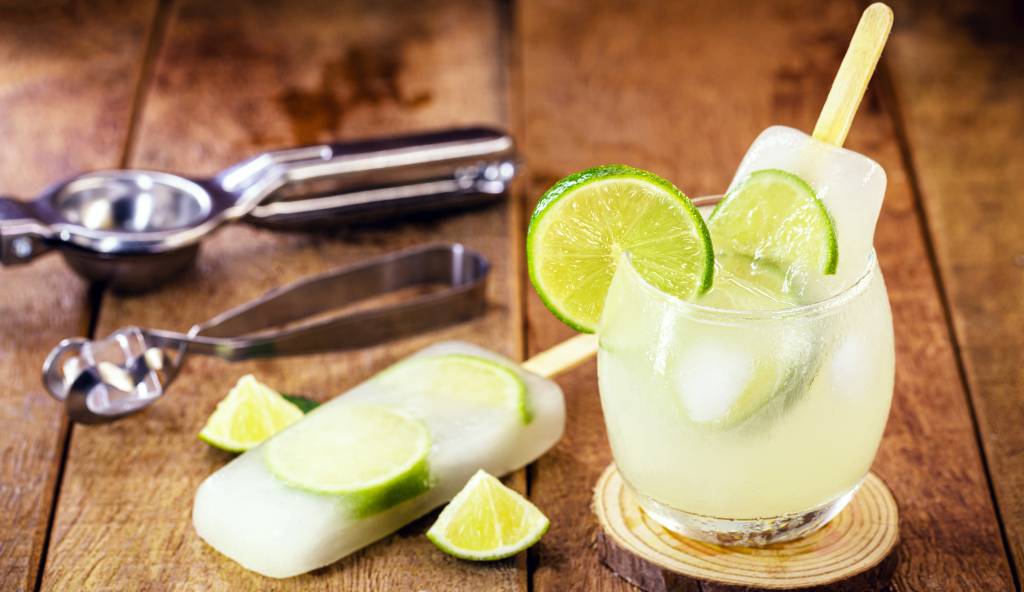 Brazilian caipirinha in popsicle, typical Brazilian cocktail made with lemon, cachaça and sugar. Traditional summer drink from Brazil. Brazilian caipirinha in popsicle, typical Brazilian cocktail made with lemon, cachaça and sugar. Traditional summer drink from Brazil.