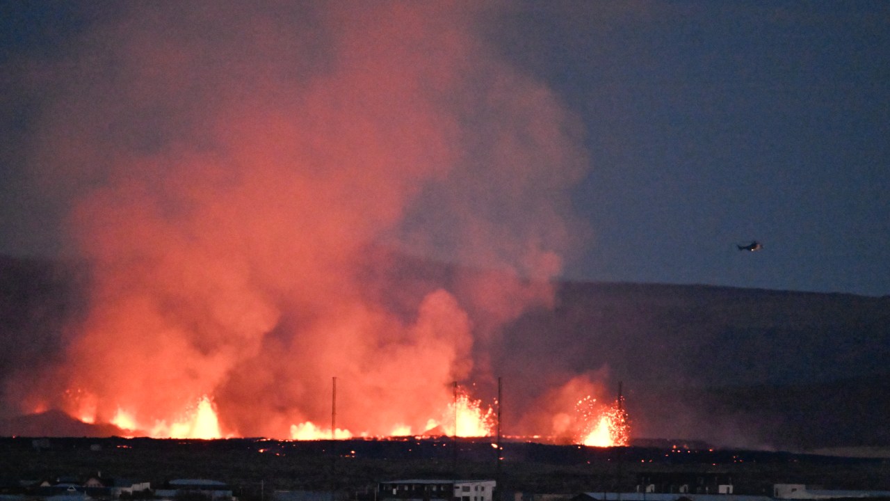 A helicopter flies near lava explosions and smoke near residential buildings in the southwestern Icelandic town of Grindavik after a volcanic eruption on January 14, 2024. Seismic activity had intensified overnight and residents of Grindavik were evacuated, Icelandic public broadcaster RUV reported. This is Iceland's fifth volcanic eruption in two years, the previous one occurring on December 18, 2023 in the same region southwest of the capital Reykjavik. Iceland is home to 33 active volcano systems, the highest number in Europe. (Photo by Halldor KOLBEINS / AFP)