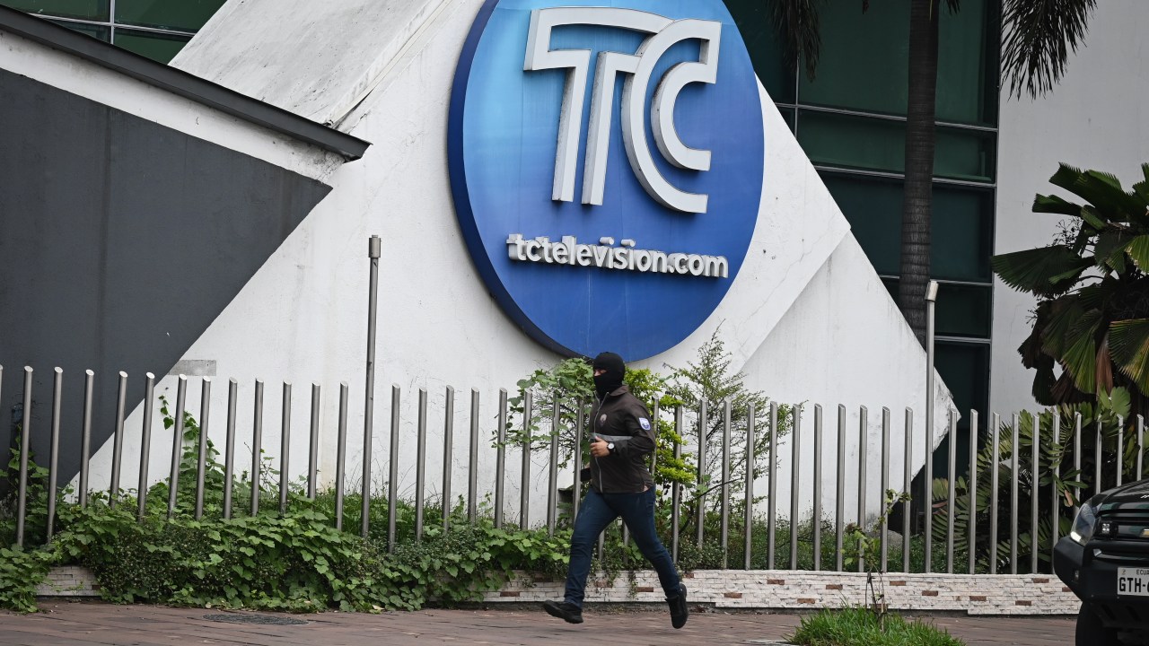 Homem com rosto coberto em frente ao prédio da TC Televisión, em Guayaquil, no Equador, após invasão de estúdio por homens armados