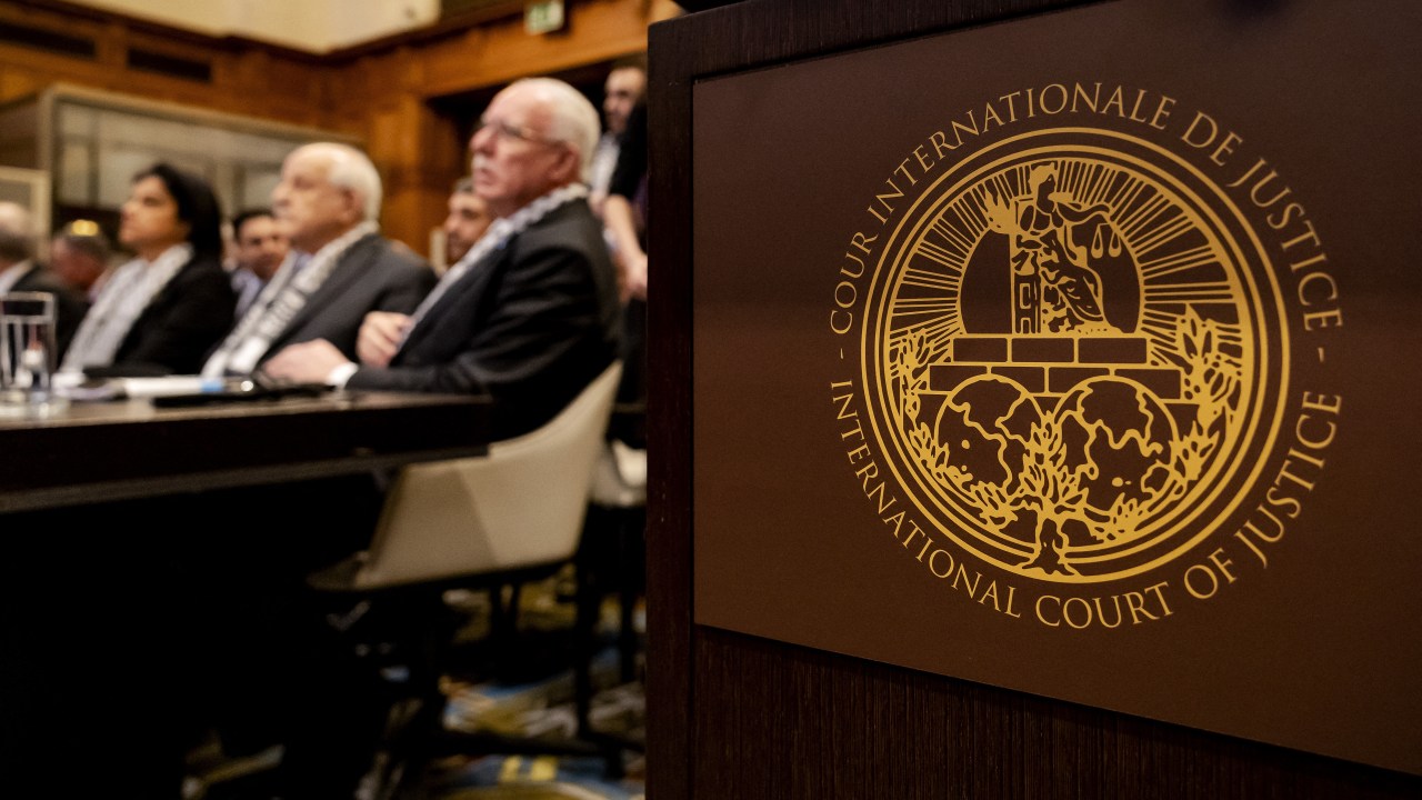 The Logo of the International Court of Justice (ICJ) is seen next to Minister of Foreign Affairs of the Palestinian Authority Riyad al-Maliki (R) and members of his delegation as they listen at the start of a hearing at the ICJ on the legal consequences of the Israeli occupation of Palestinian territories, in The Hague on February 19, 2024. (Photo by Robin van Lonkhuijsen / ANP / AFP) / Netherlands OUT