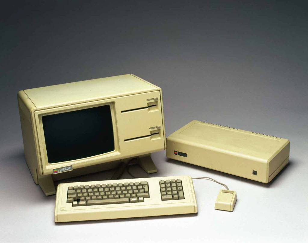 4–COMPUTADOR-APPLE-LISA-1984.jpg LISA, de 1983 - Vinha com interface gráfica, sem as letrinhas sem graça na tela. O mouse, feioso que só ele, mal podia ser usado, por ausência de programas.
