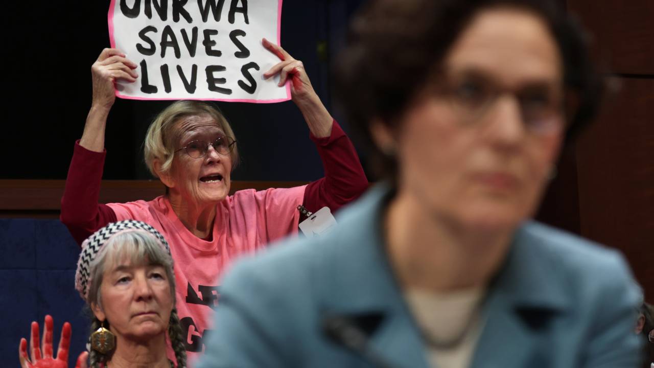 Uma mulher protesta com cartaz "UNRWA salva vidas" durante audiência do Comitê de Relações Exteriores da Câmara, nos Estados Unidos. 30/01/2024