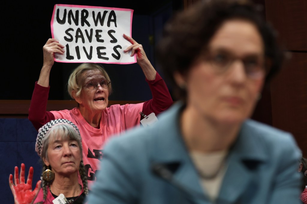 Uma mulher protesta com cartaz "UNRWA salva vidas" durante audiência do Comitê de Relações Exteriores da Câmara, nos Estados Unidos. 30/01/2024