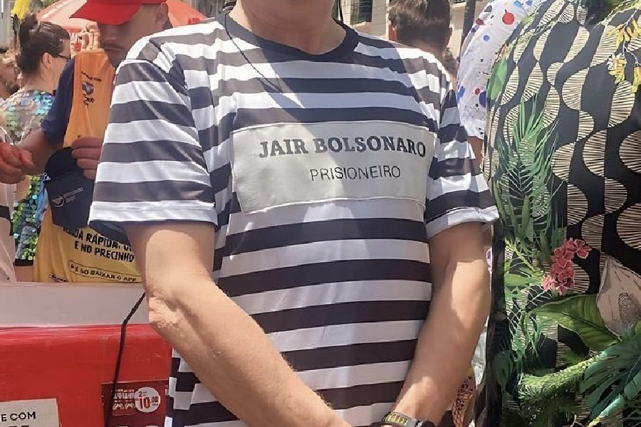 Folião usa fantasia de uniforme de presidiário e placa com o nome do ex-presidente Jair Bolsonaro (PL) em bloco de Carnaval