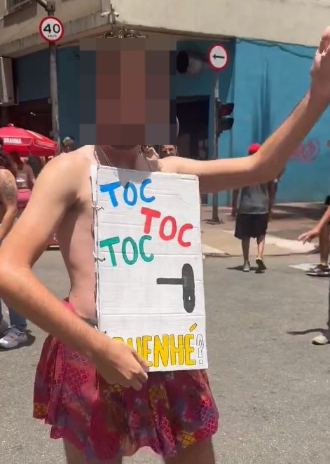 Folião usa fantasia com placa imitando porta e os dizeres "Toc toc toc", em alusão a meme sobre Polícia Federal
