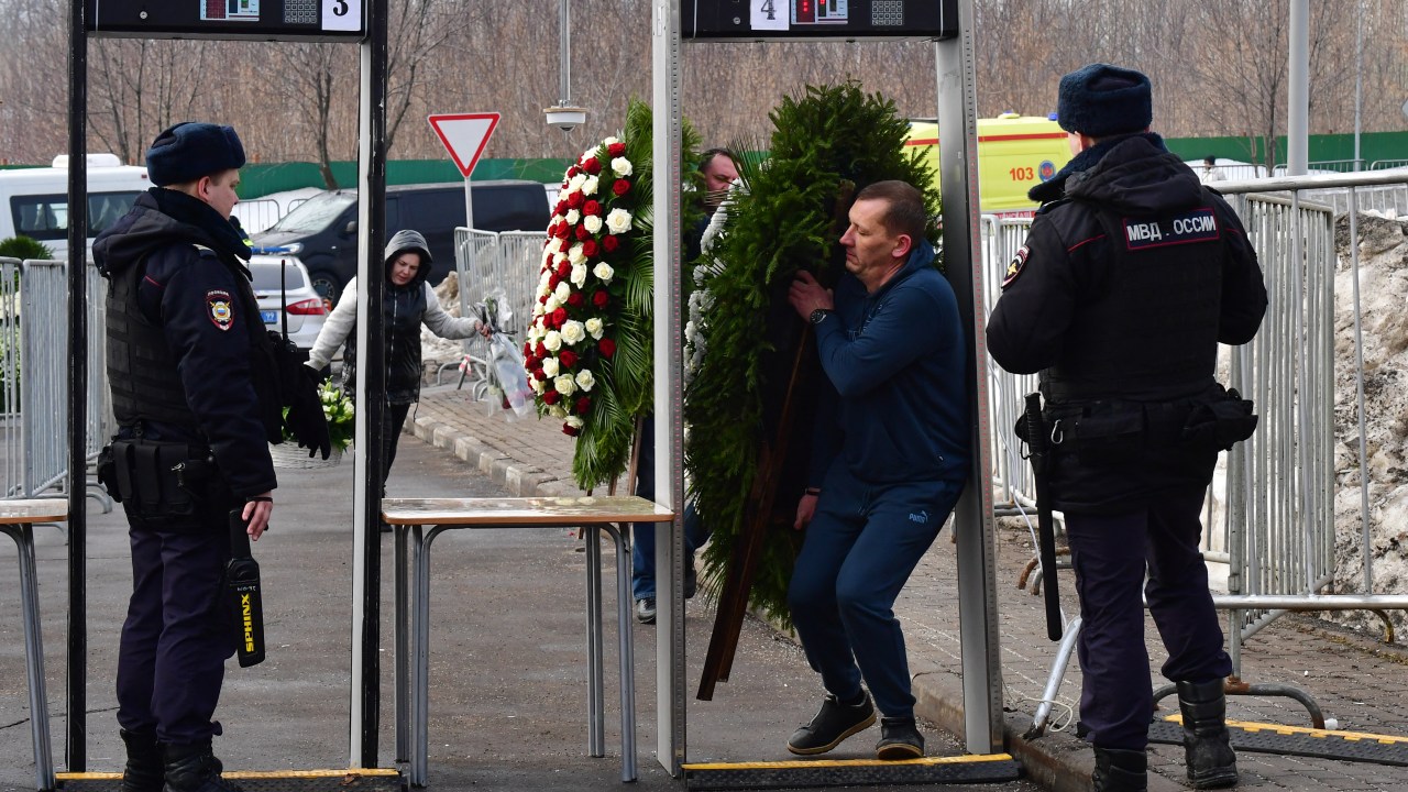 A man carrying a wreath passes through a metal detector security gate at the Borisovo cemetery ahead of the burial of late Russian opposition leader Alexei Navalny in Moscow's district of Maryino on March 1, 2024. (Photo by Olga MALTSEVA / AFP)