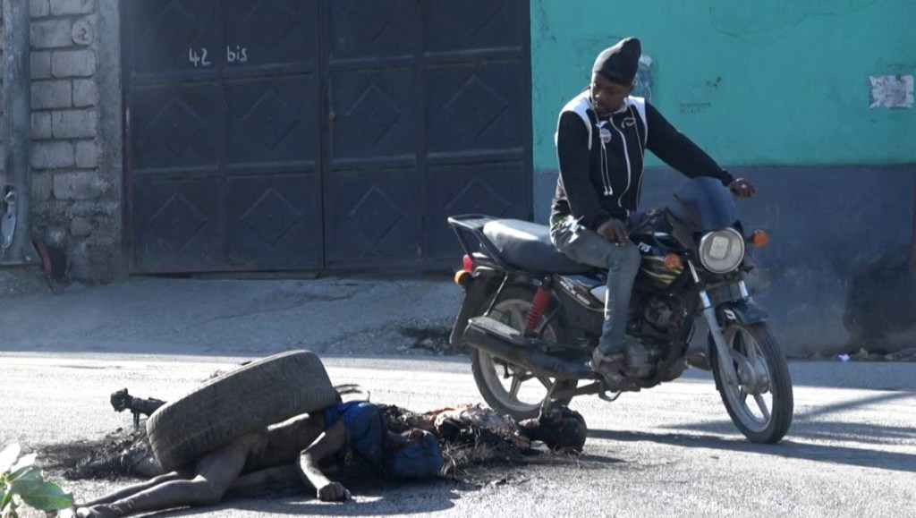 Homem observando corpos mortos após o ataque na Penitenciária Nacional de Porto Príncipe. 03/03/2024