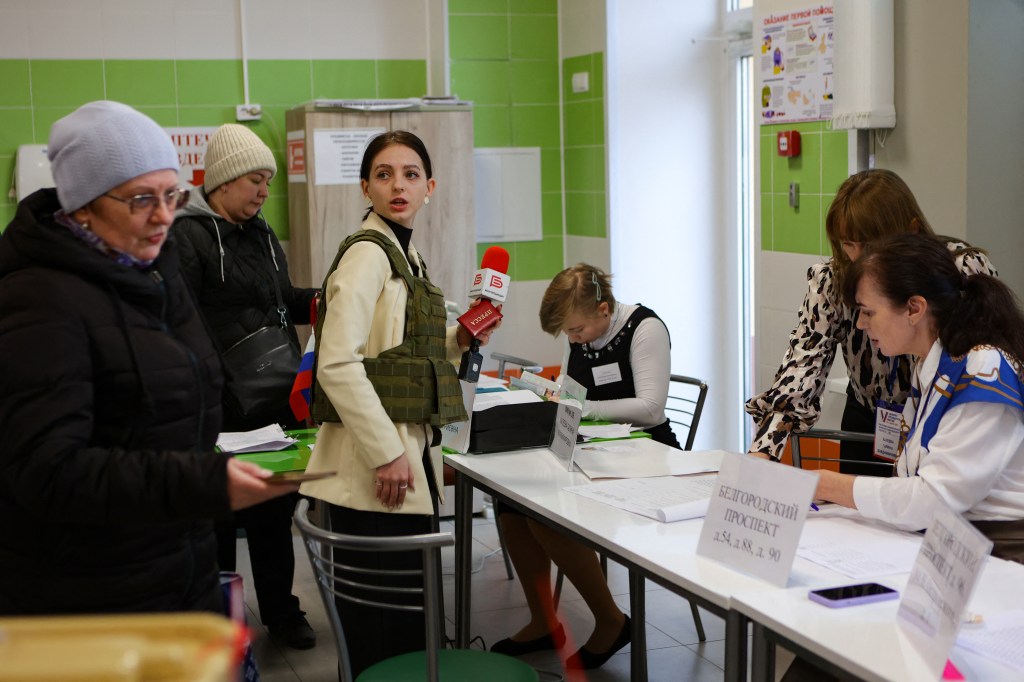 A journalist wearing a flak jacket works at a polling station during Russia's presidential election in Belgorod on March 15, 2024. (Photo by STRINGER / AFP)