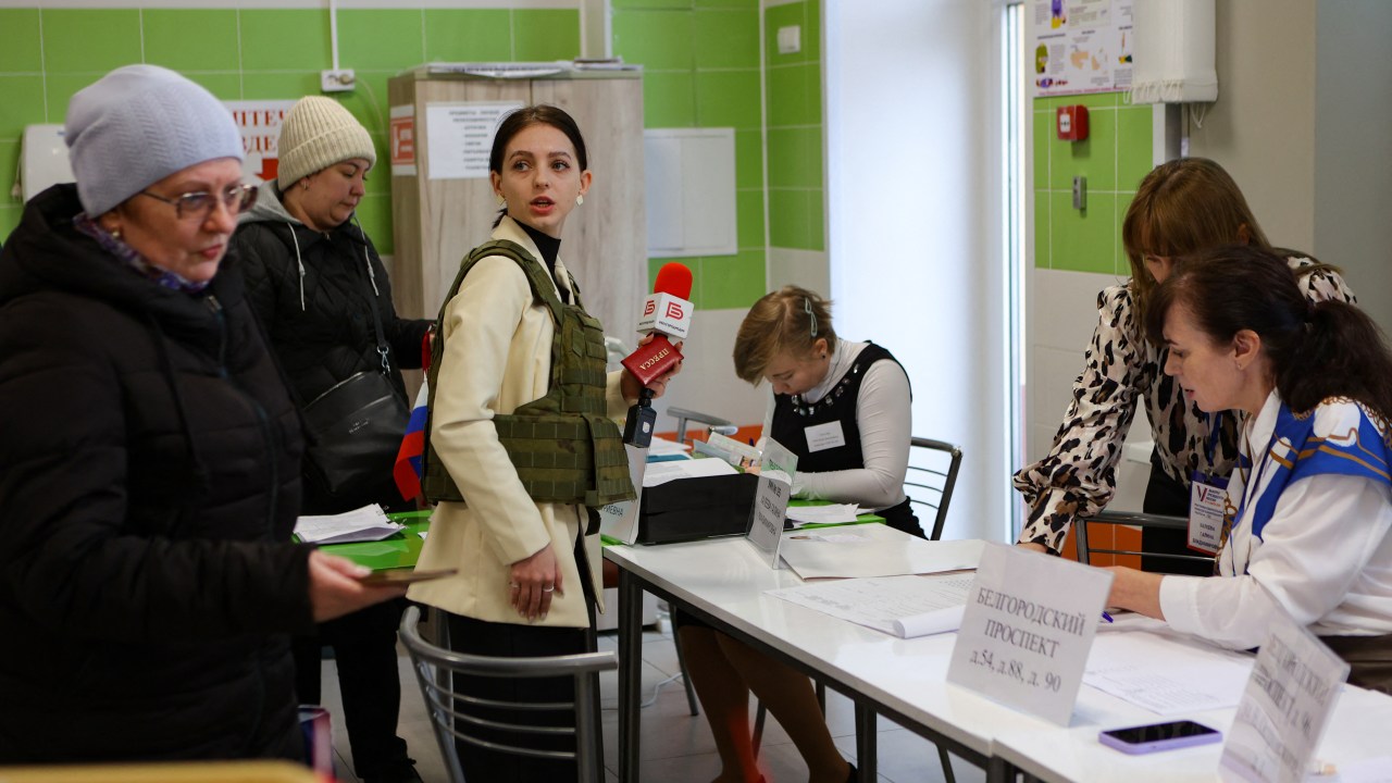 A journalist wearing a flak jacket works at a polling station during Russia's presidential election in Belgorod on March 15, 2024. (Photo by STRINGER / AFP)