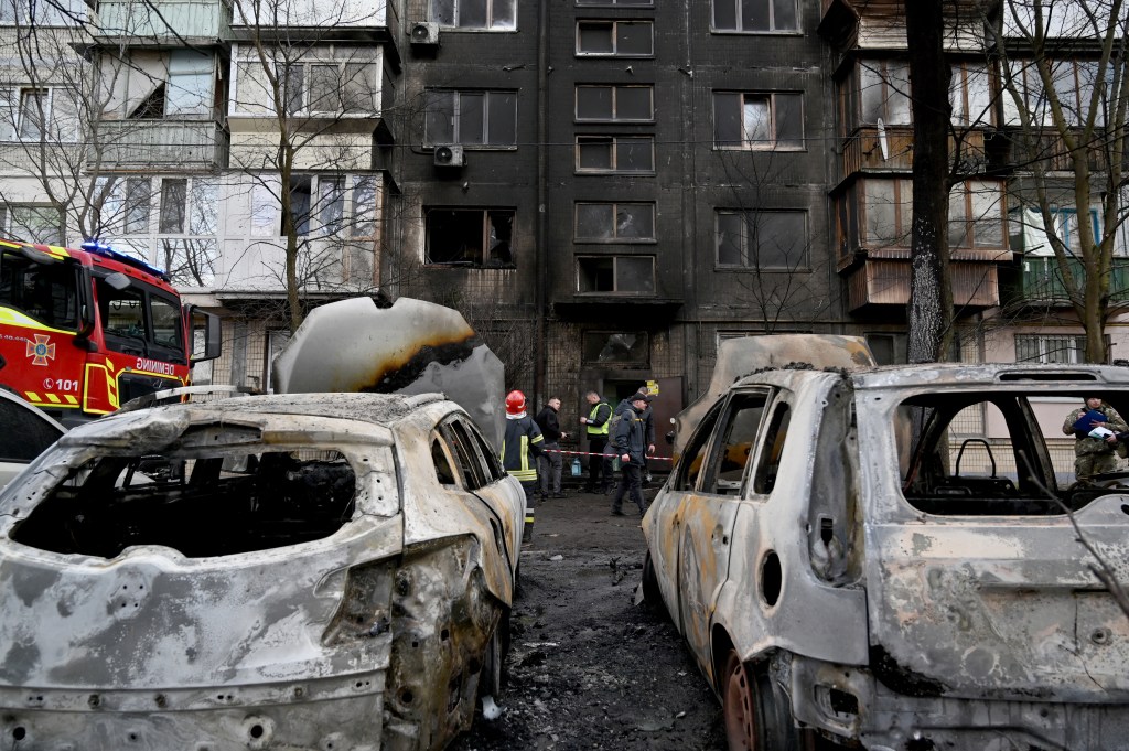 Autoridades avaliando a situação dos prédios residenciais e carros atingidos pelos destroços do ataque russo à Kiev. 21/03/2024