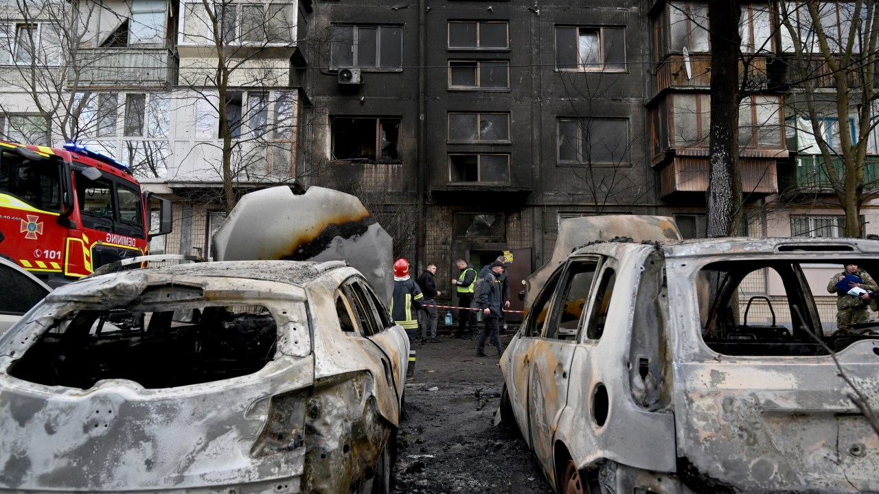 Autoridades avaliando a situação dos prédios residenciais e carros atingidos pelos destroços do ataque russo à Kiev. 21/03/2024