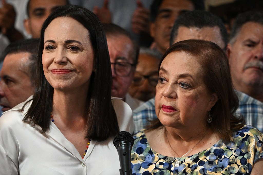 Venezuelan opposition leader Maria Corina Machado (L) gestures next to her replacement for the upcoming national elections, Corina Yoris (R), during a press conference in Caracas, on March 22, 2024. Machado announced this Friday that Corina Yoris, philosopher and university professor, will be the candidate to represent her in the presidential elections on July 28 in which she will face President Nicolas Maduro. (Photo by Federico Parra / AFP)