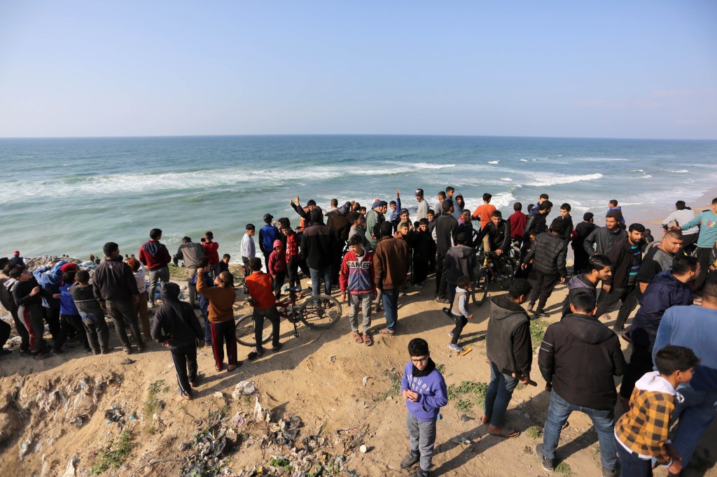 Palestinos aguardam lançamento aéreo de ajuda humanitária na praia de Deir al Balah, em Gaza. 27/02/2024