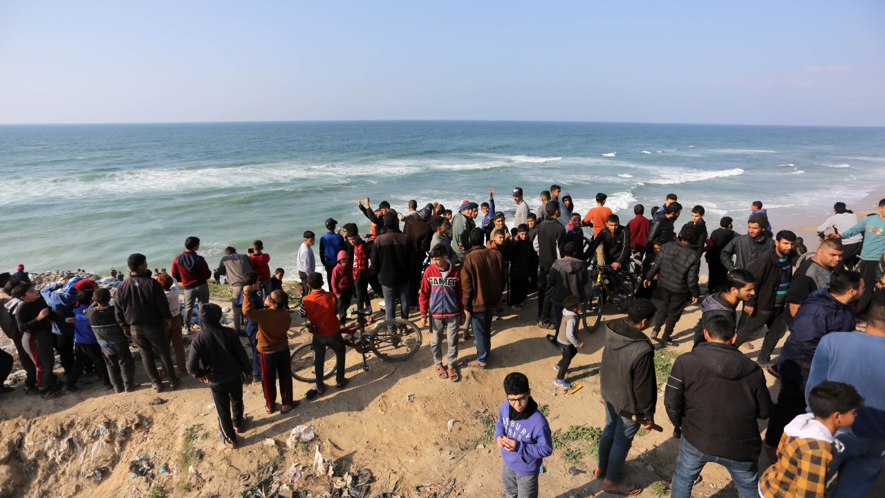 Palestinos aguardam lançamento aéreo de ajuda humanitária na praia de Deir al Balah, em Gaza. 27/02/2024