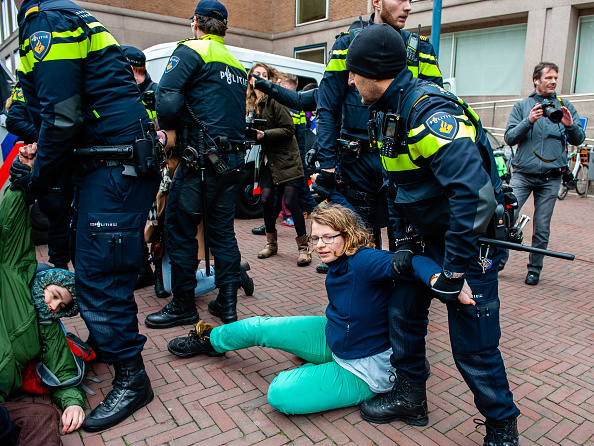 Policial prendendo jovem ativista durante protesto na Holanda. 31/01/2020